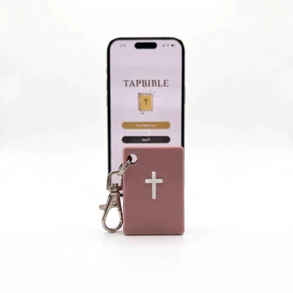 Light Pink TapBible Catholic NFC Bible keychain with a white cross in front of a phone showing the TapBible app