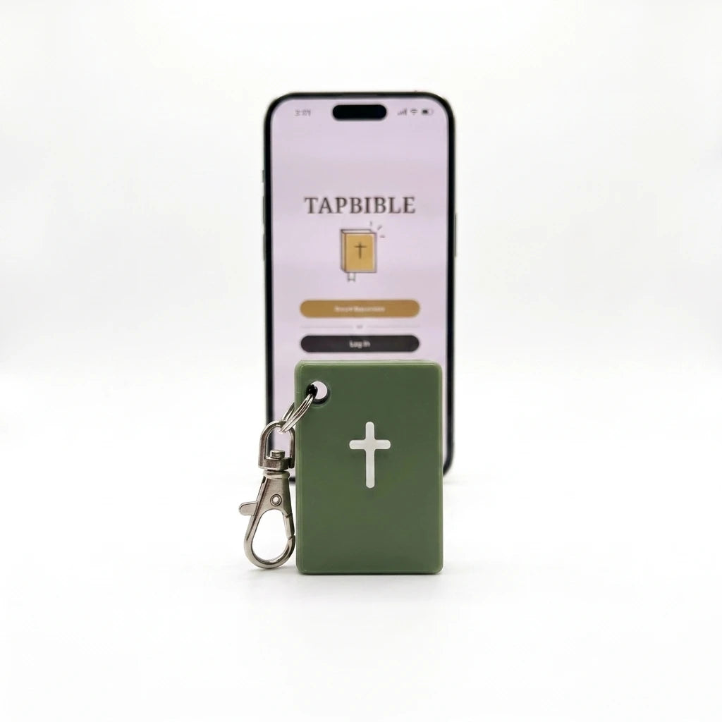 Sage green TapBible Catholic NFC Bible keychain with a white cross in front of a phone showing the TapBible app