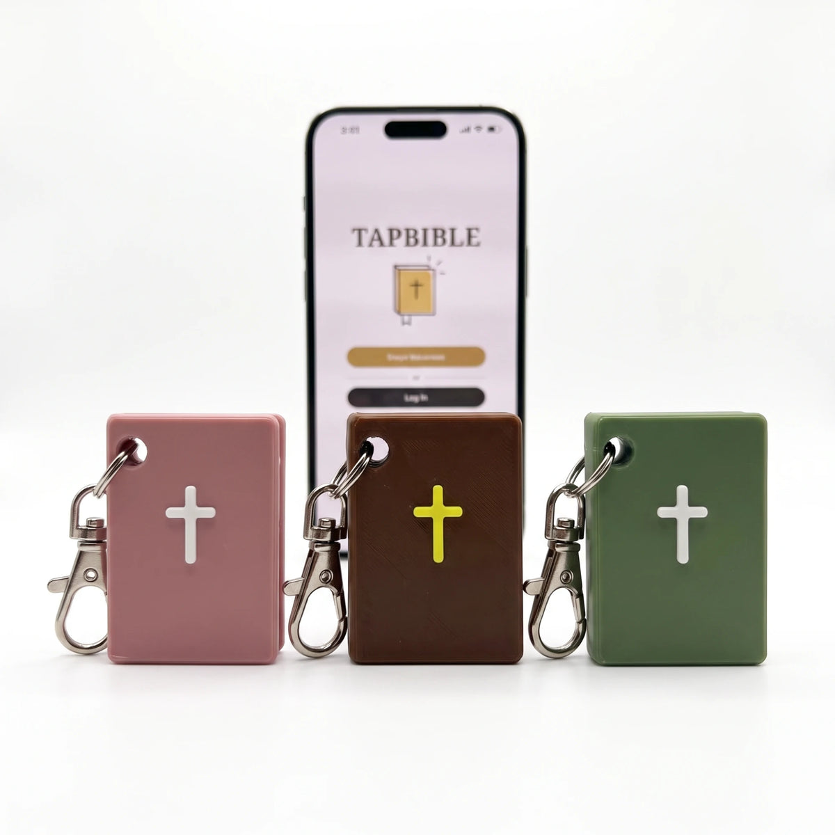 TapBible Catholic NFC Bible keychains in Light Pink, Brown and Sage with a phone showing the TapBible app